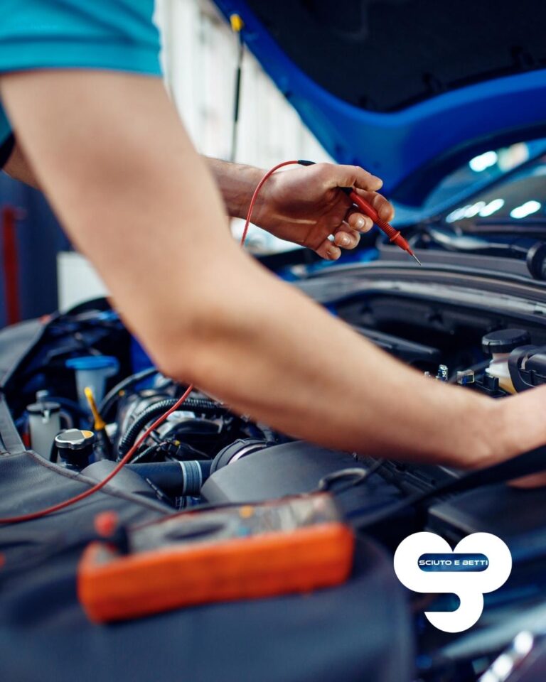 SCIUTO ELETTRAUTO a Grosseto - A mechanic in a blue shirt is testing a car's engine with a multimeter.